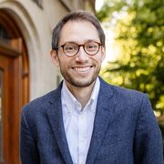 Rev. Schuyler Vogel, College Chaplain, wearing a blue sports coat, with a white collared shirt underneath and glasses