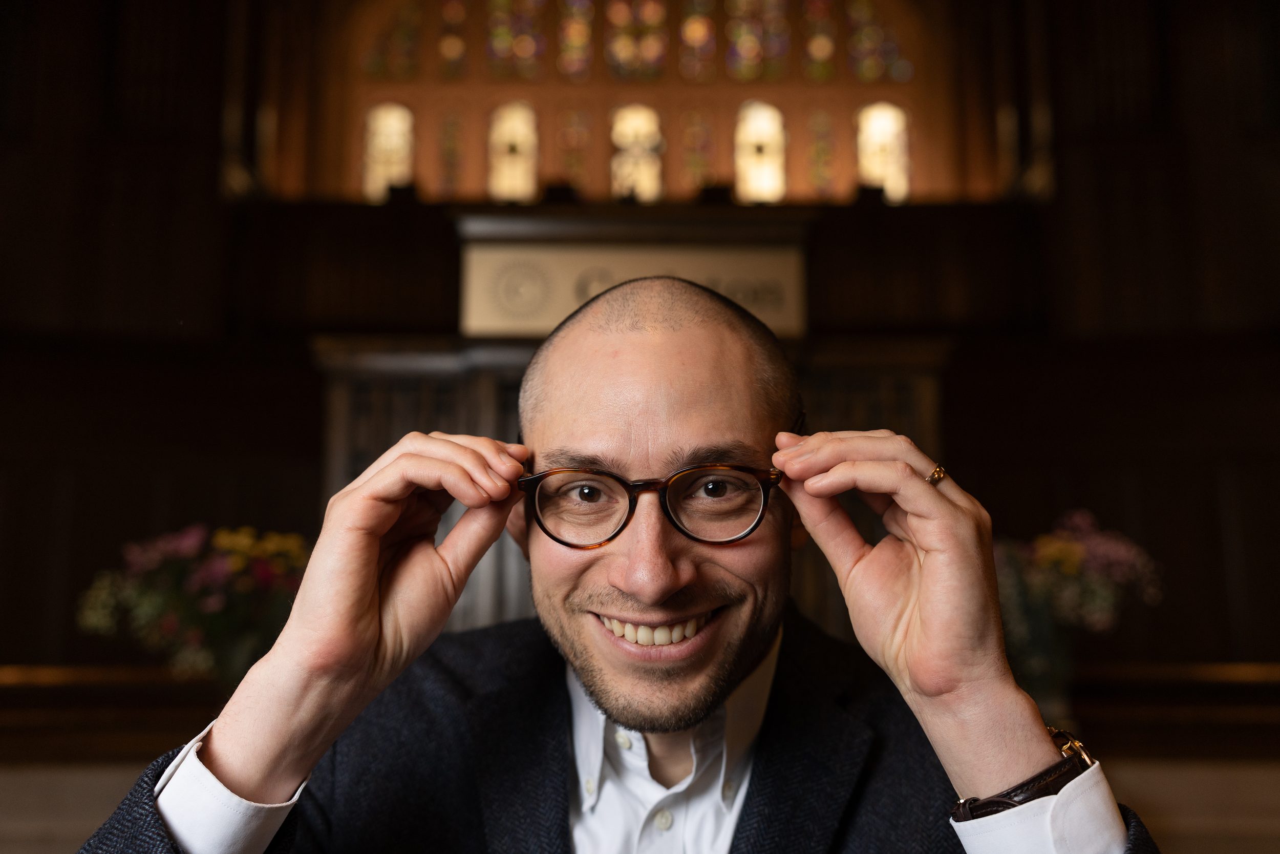 Rev. Schuyler Vogel with a big smile and his hands reaching up to hold onto his glasses