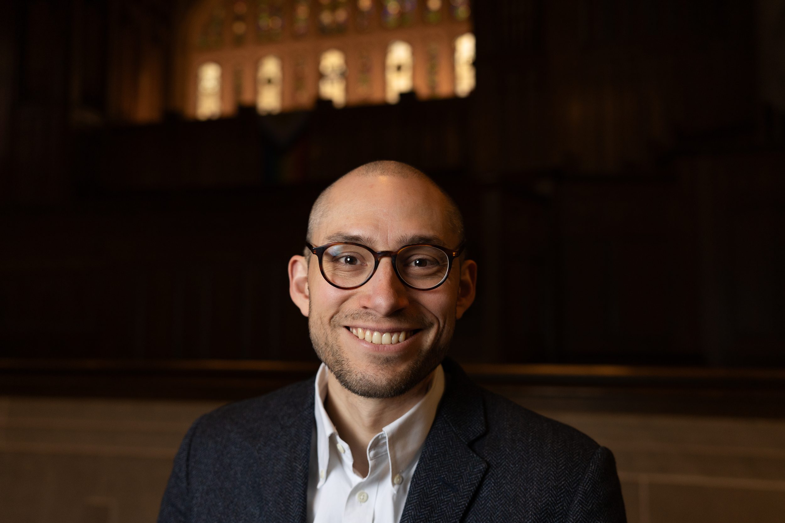 Rev. Schuyler Vogel, College Chaplain, wearing glasses, a white collared shirt and dark blue suit jacket