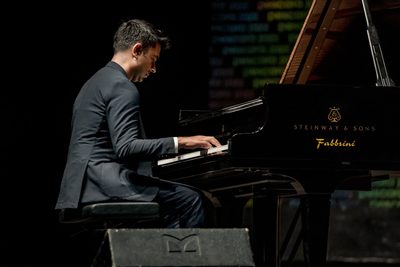 Person sitting with their back turned playing a piano