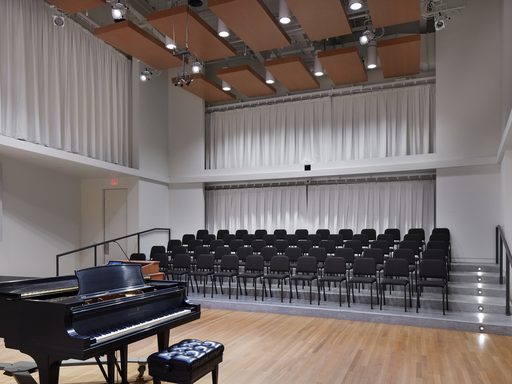 Applebaum Recital Hall, a choir rehearsal space, with piano, risers, and chairs.