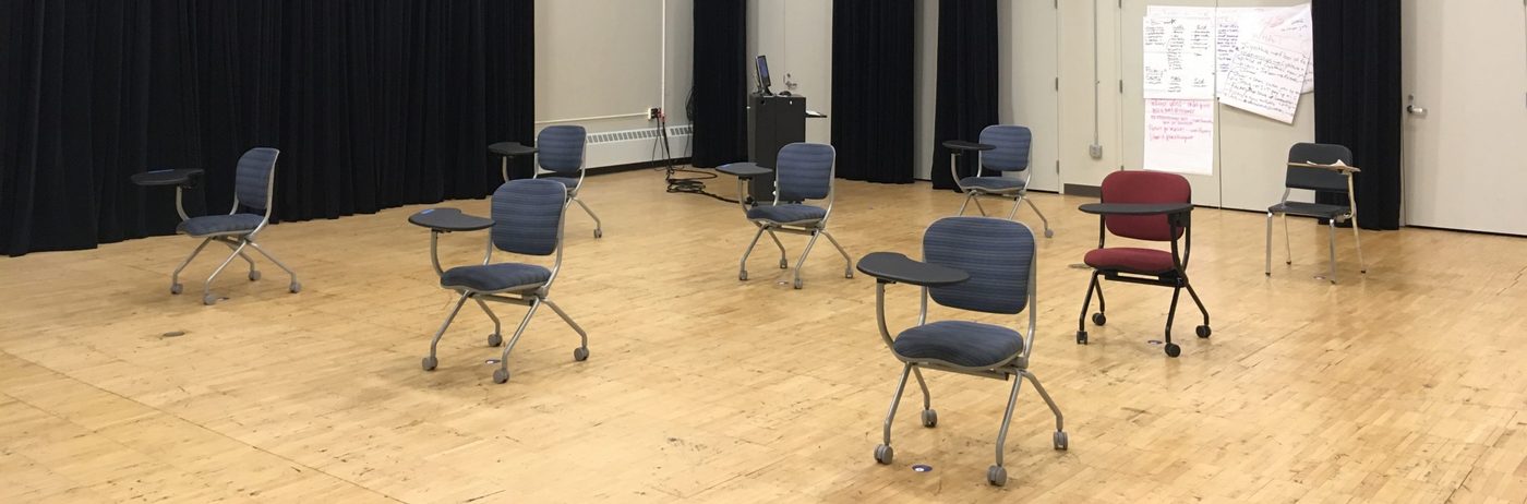 Several rolling chairs spread out among the rehearsal studio on hardwood floors