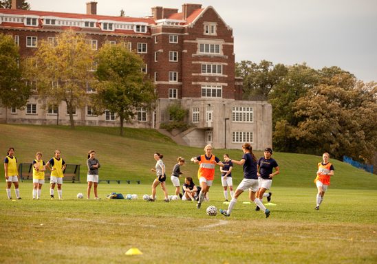 students play soccer with Evans Hall in the background