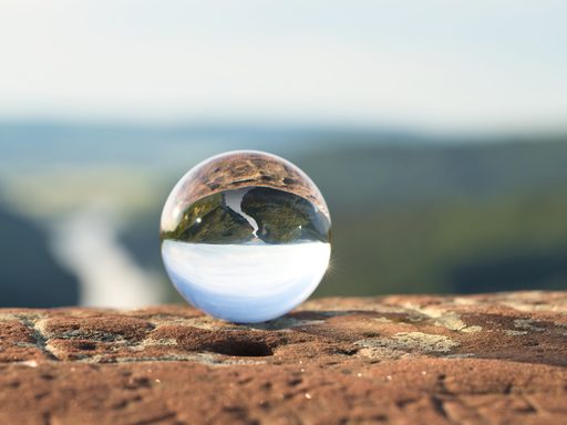 A transparent sphere reflects surrounds in an outdoor setting