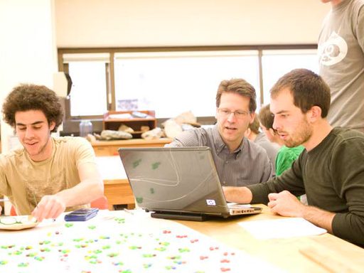 Students and professor looking at a laptop