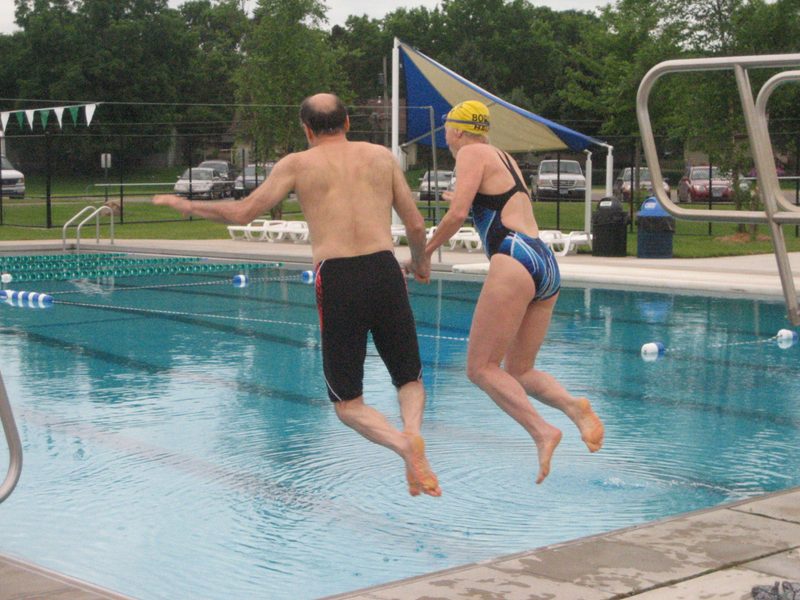 Two people jump into a pool