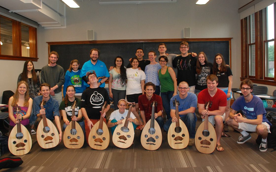 A group of students pose with musical instruments in a classroom