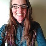 Photo of a woman smiling with long hair and glasses