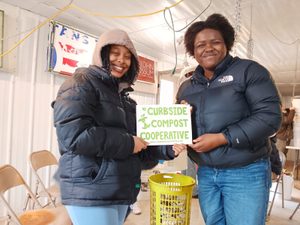 Smiling students holding a Curbside Compost Cooperative sign