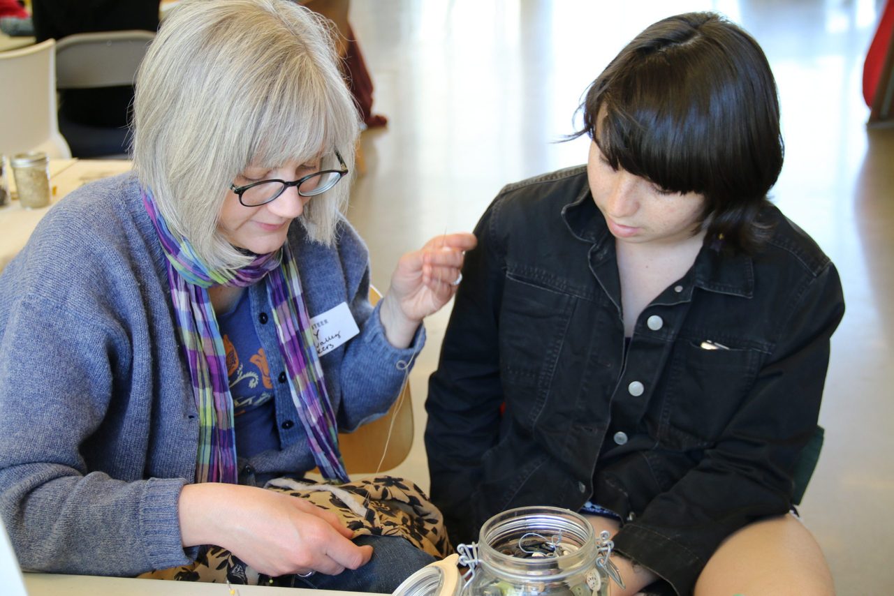 A community member helps a student repair an item at the Repair Fair.