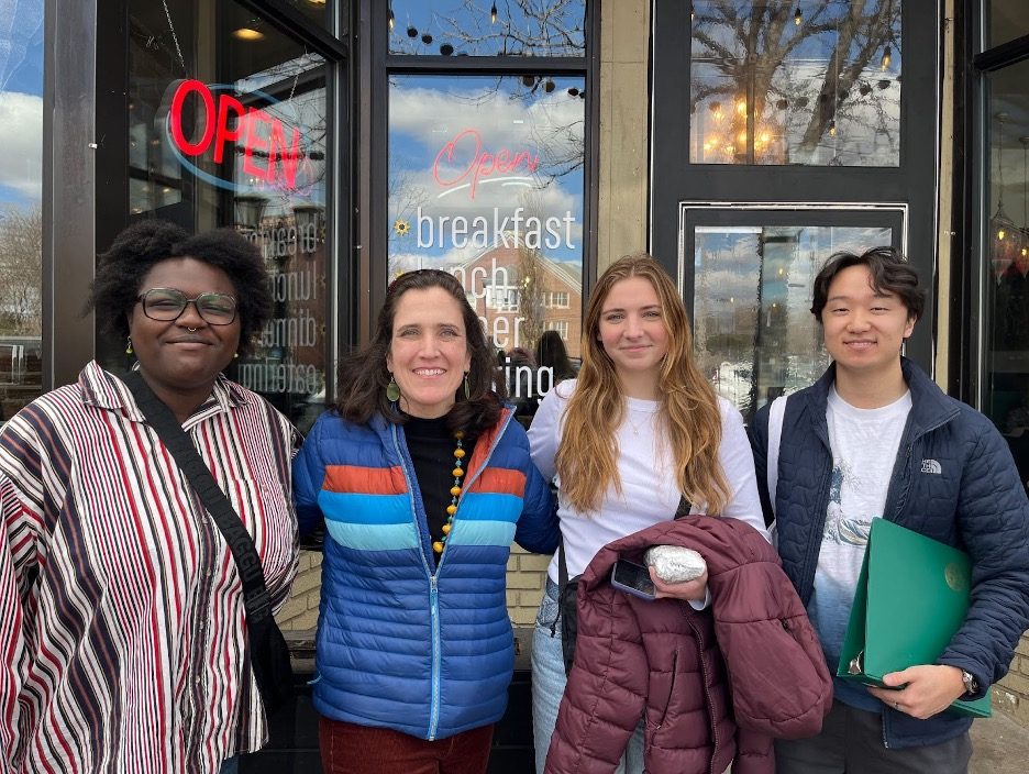 group poses for photo outside restaurant window