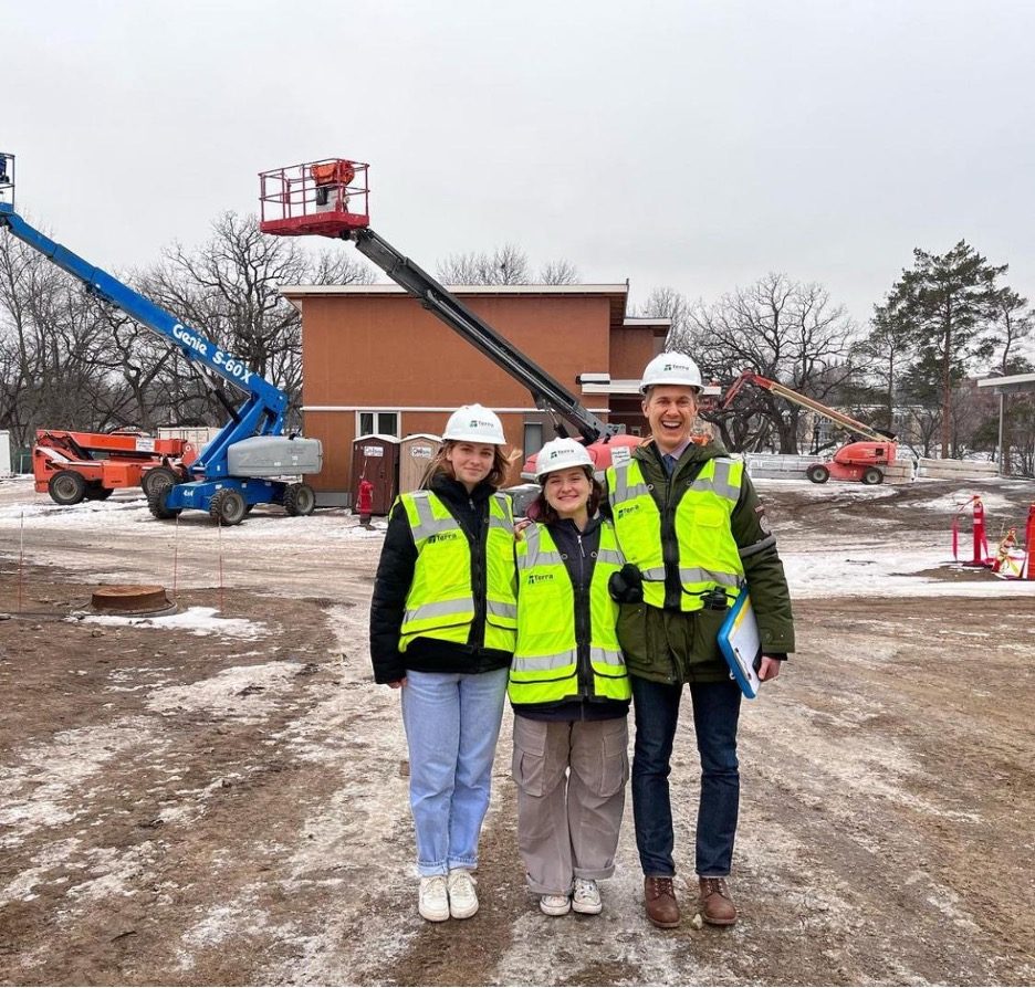 group of three wearing safety vests and hard hats at a construction site