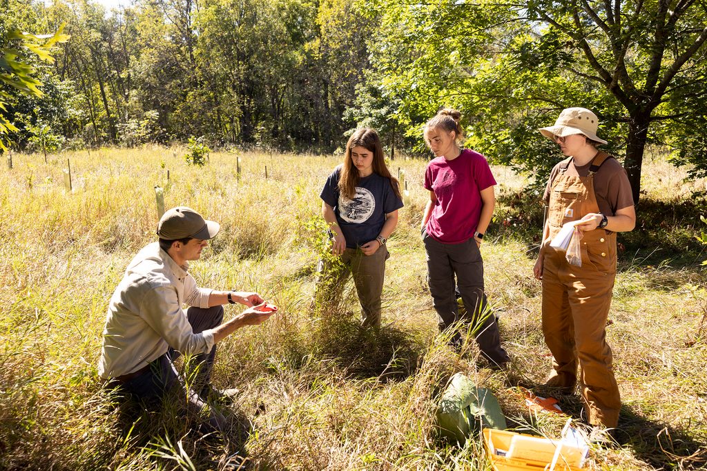 Professor talking to three students in the Carleton arboretum