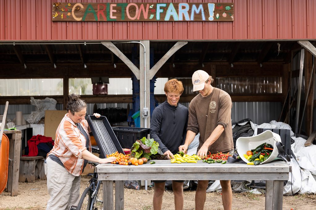 Amanda Sames, farm manager, with students, George and Aley, at the student farm, sorting produce