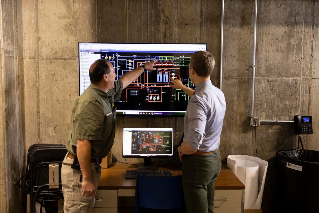 Two men looking at a geothermal system monitoring screen