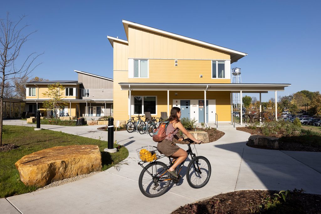 Student biking in front of passive solar, sustainable student housing buildings on Carleton College's campus