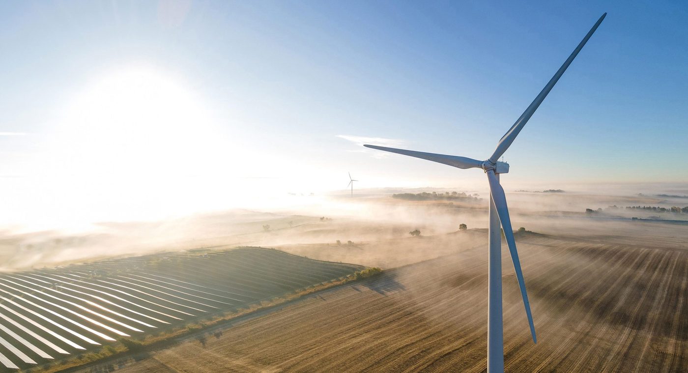 Wind turbines and solar panels on a foggy morning
