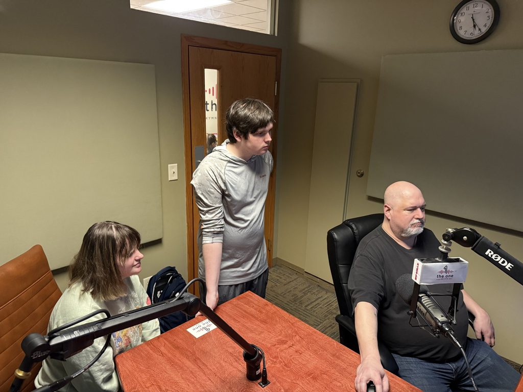 three individuals in a radio booth
