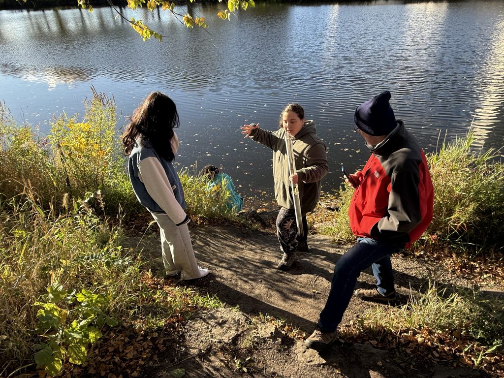 students testing water on a riverbank