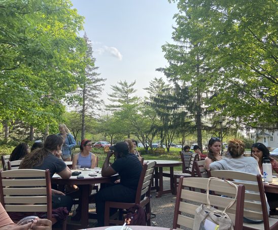 GWSS students and faculty conversing and enjoying food on the AGH patio for the spring '23 Strawberries & Chocolate Celebration.