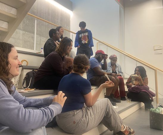 GWSS students and faculty conversing and enjoying food in the Weitz basement for the spring '24 Strawberries & Chocolate Celebration