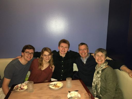 Five people pose for a photo in a restaurant
