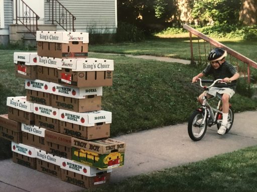 A boy rides a bike into a stack of boxes