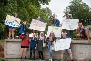 A group of students holding "welcome to Carleton" signs