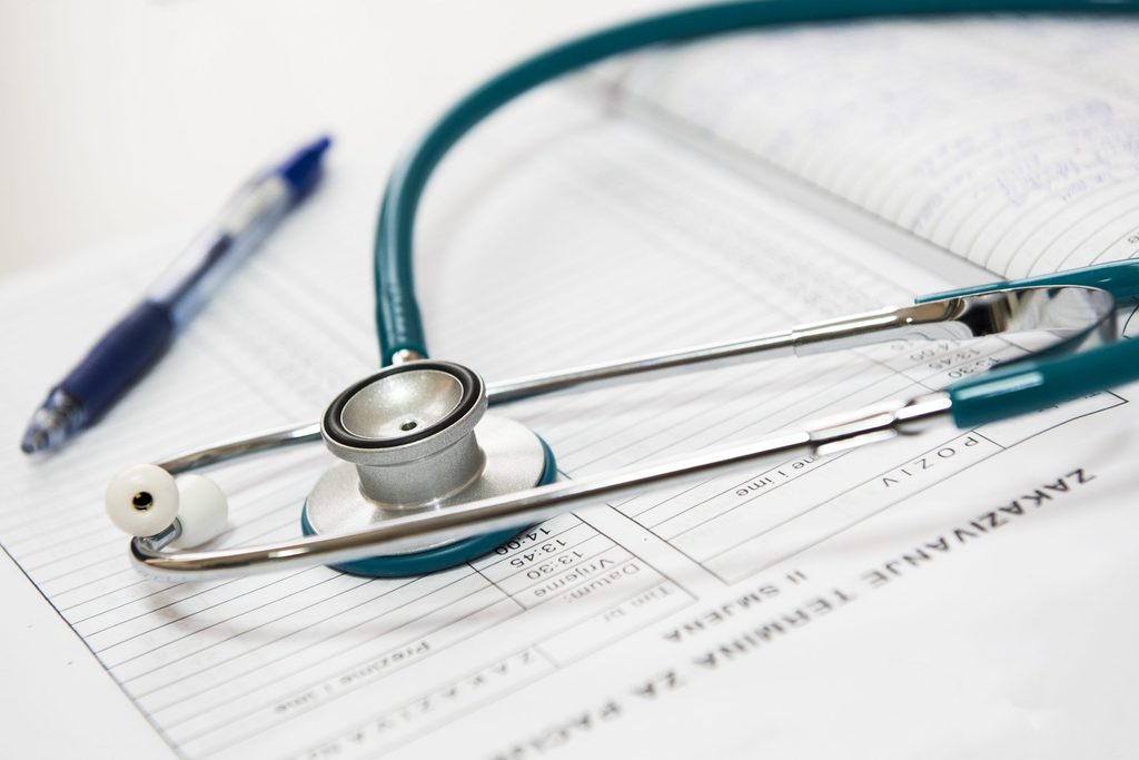 Photograph of a stethoscope and pen placed on top of papers.