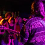 performer plays guitar, facing audience