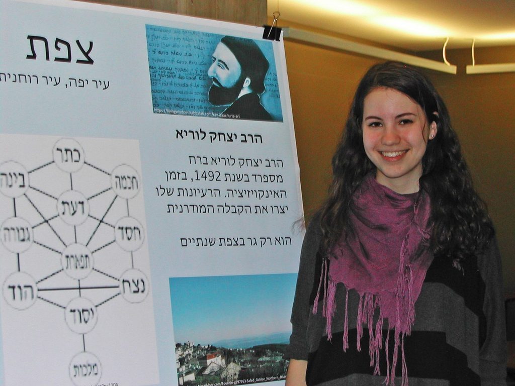 Evie Rosenberg '17 stands beside a poster in Hebrew