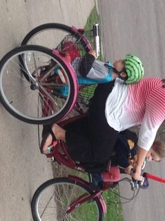 Constanza Ocampo-Raeder riding her red tricycle with her kids