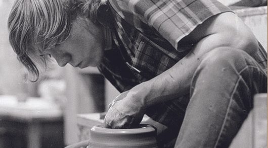 A Carleton student working with clay on a potter's wheel