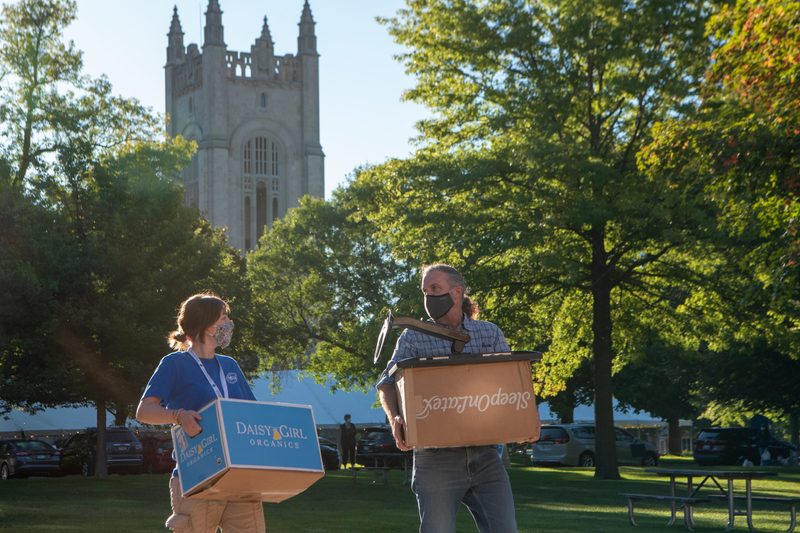 A student and adult with moving boxes with the chapel in the background.