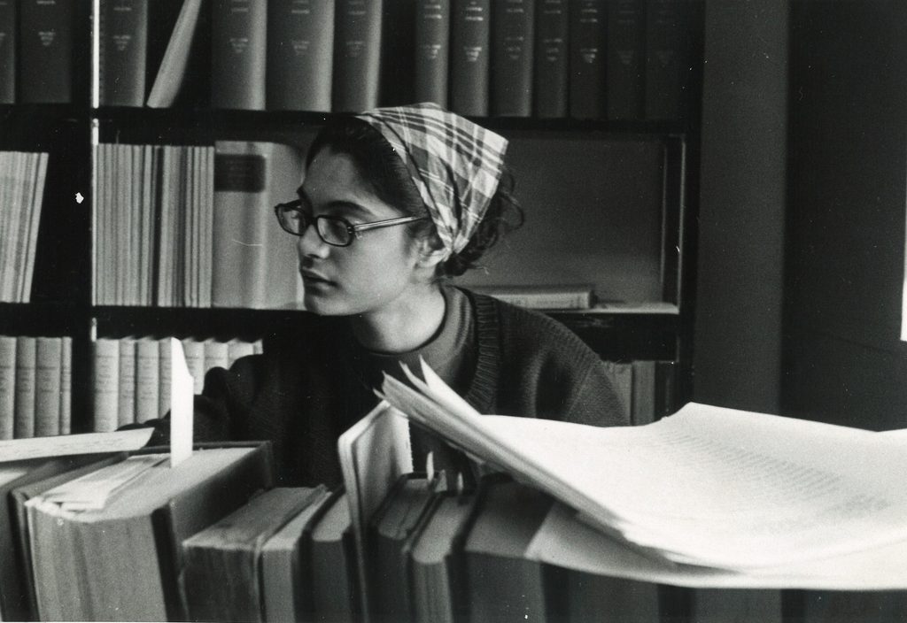 A college student looks through a stack of books in the 1960s.