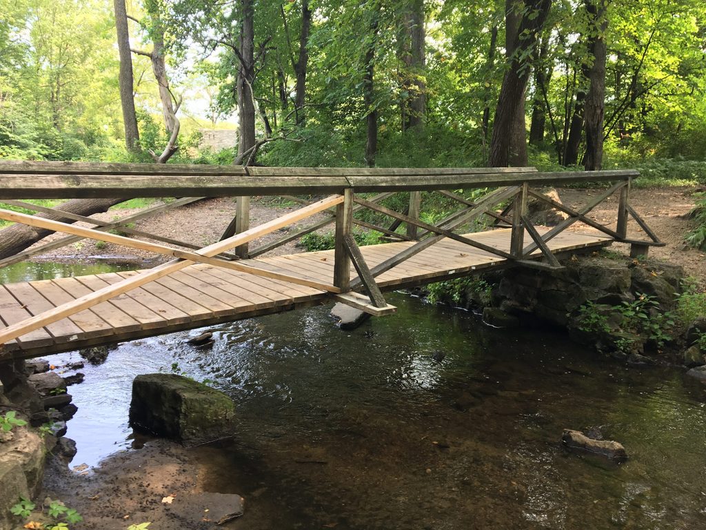 A wooden walking bridge over a small creek.