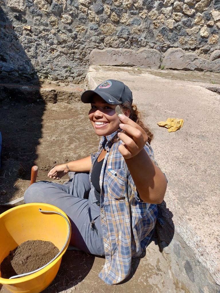 Sidra Michael '23 holds up a find in an archaeological trench in Pompeii.