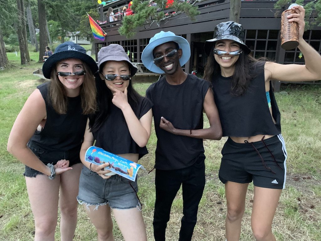 Students dressed in black with sunglasses made of mussel shells make strong-arm poses.