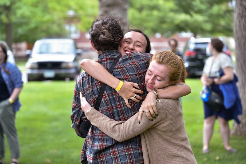 Three members of the class of 2020 hug outside the Chapel tent.