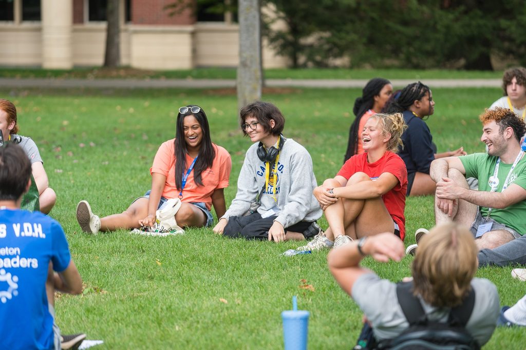 New students relax on the Bald Spot in a circle.