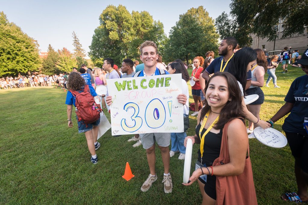 New Student Week leader holds a welcome sign for Group 30.