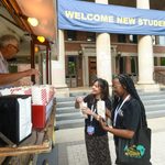 Two students grab popcorn from the popcorn cart in front of Sayles.