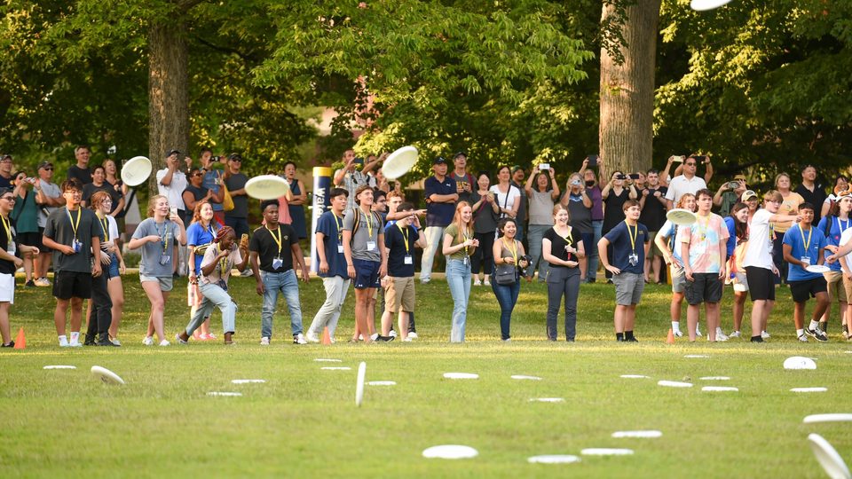 Photo taken from across the Bald Spot of students throwing their frisbees in the NSW frisbee toss.