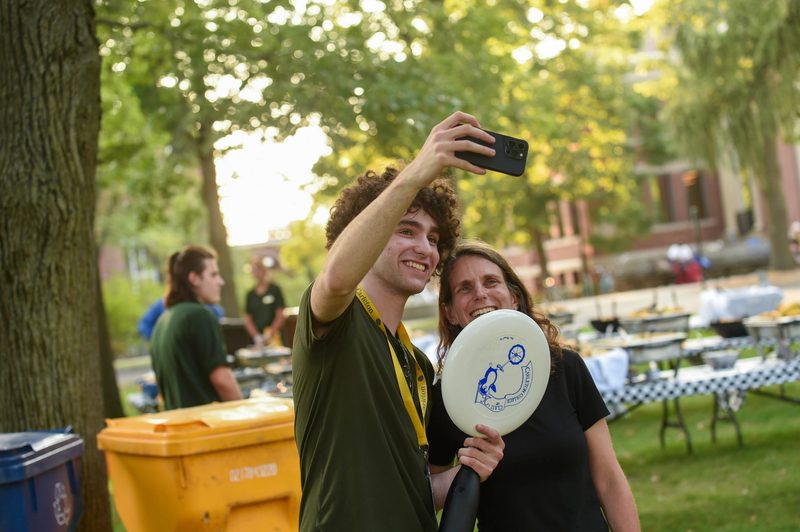 A student takes a selfie with their parent and their frisbee.