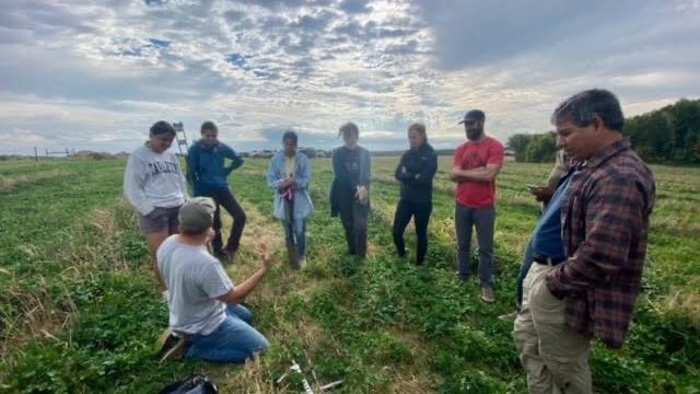 Students gather in a field with RAA co-director Regi Haslett-Marroquin and professor Dan Hernández