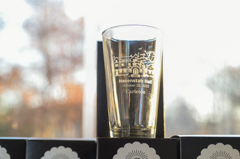Close-up of a pint glass etched with an illustration of Hasenstab Hall.