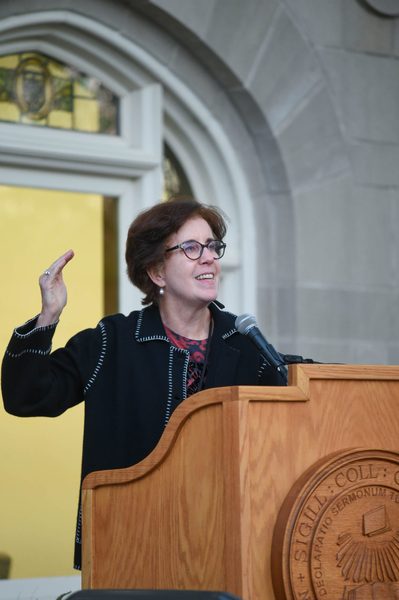 Cathy Paglia ’74 P’18 speaks at a podium in front of Hasenstab Hall.