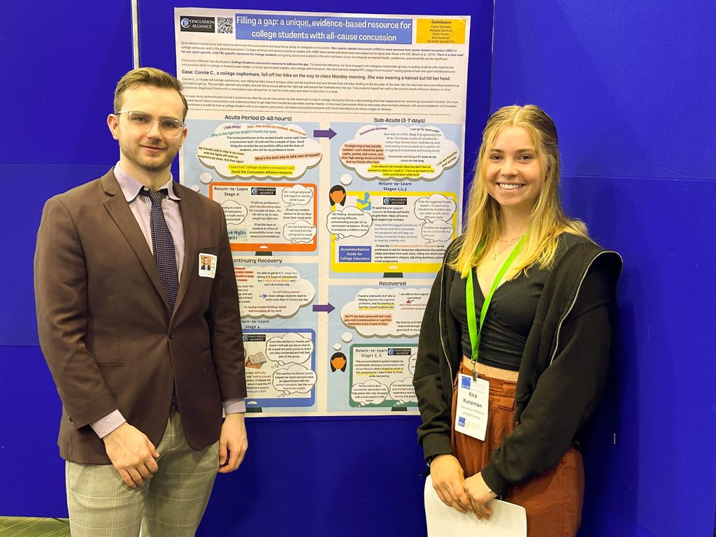 Two people with nametags smile and stand next to their research poster.