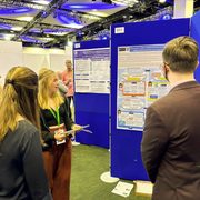 Two people present their research poster to two other people.