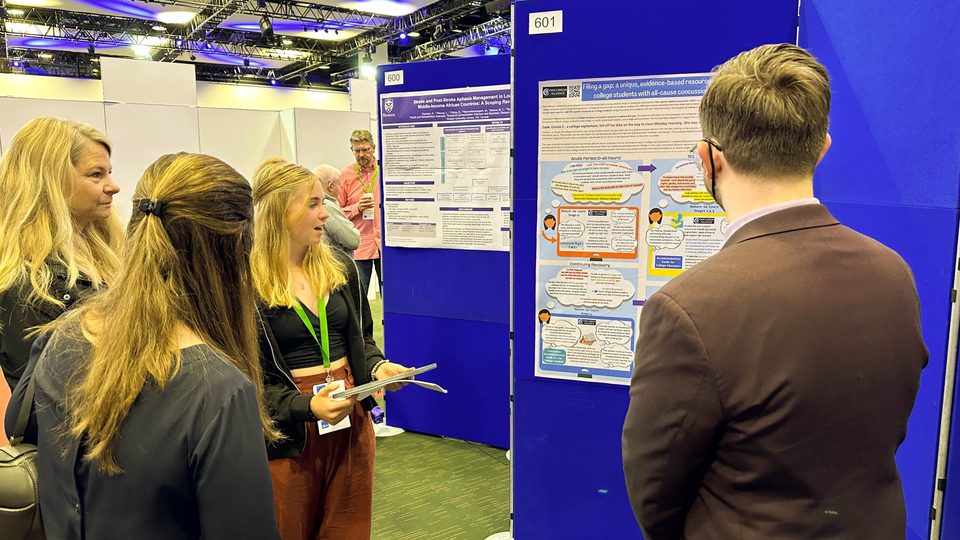 Two people present their research poster to two other people.